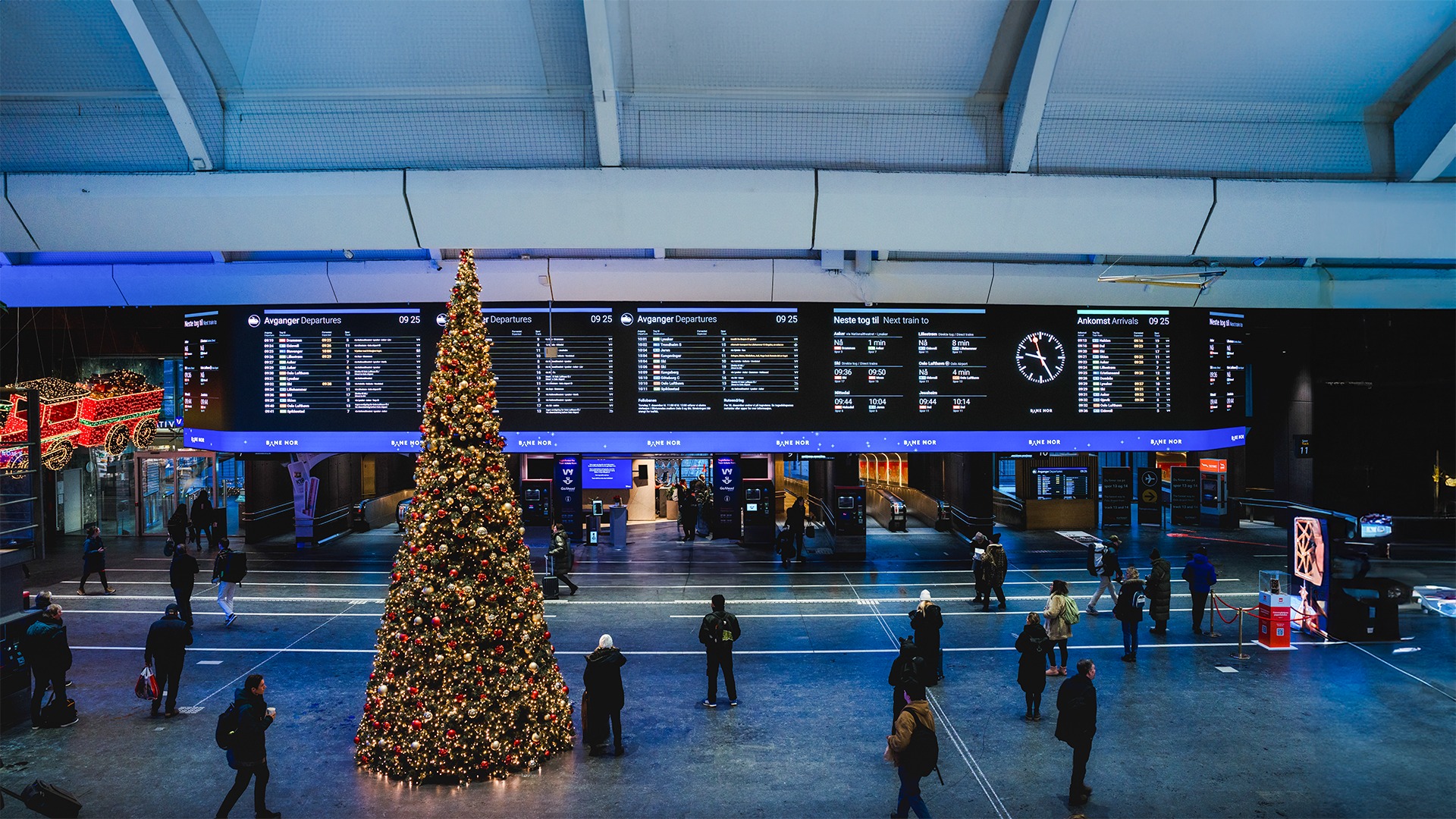 Wide indoor LED information wall in a European transport hub showing a continuous display surface for public information